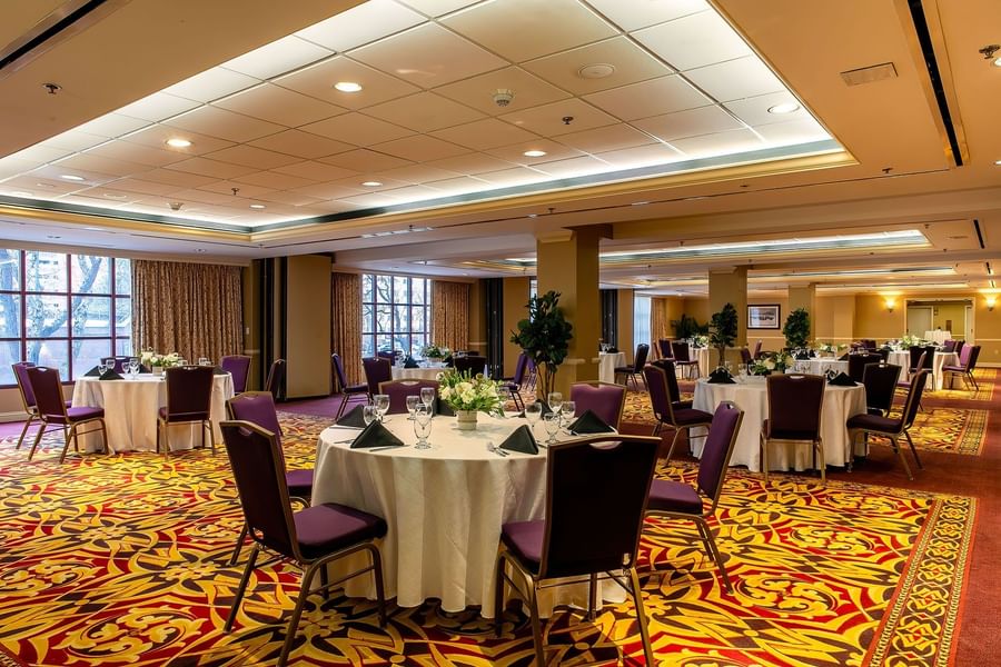 Round dining tables by purple chairs under a white ceiling on a red rug in Capitol IV at Warwick Denver