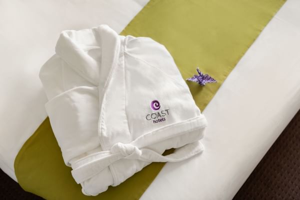 Robe with Coast Hotels emblem on bed