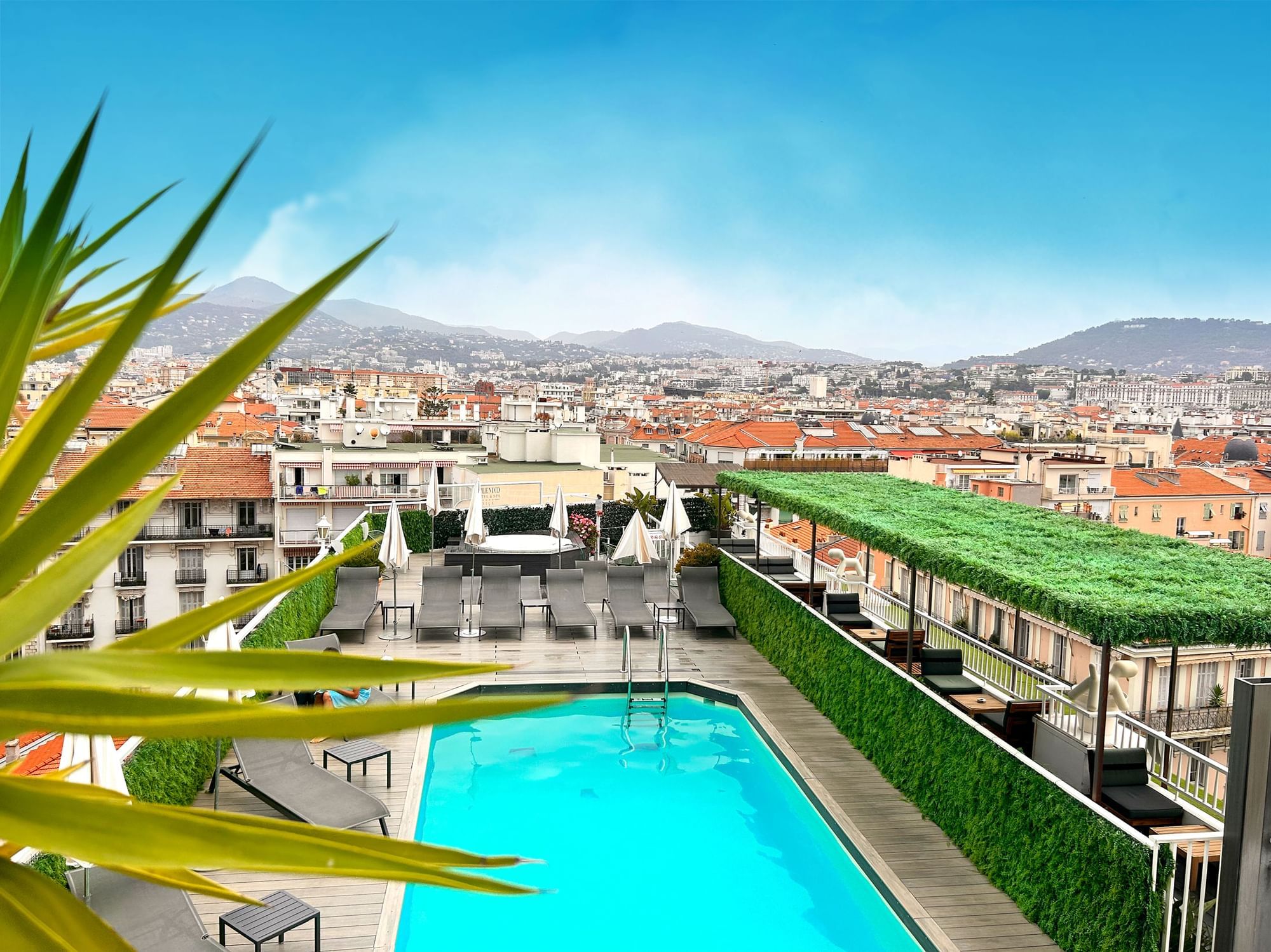 Outdoor pool, sun lounges, and dining area with city view at Splendid Hotel & Spa Nice