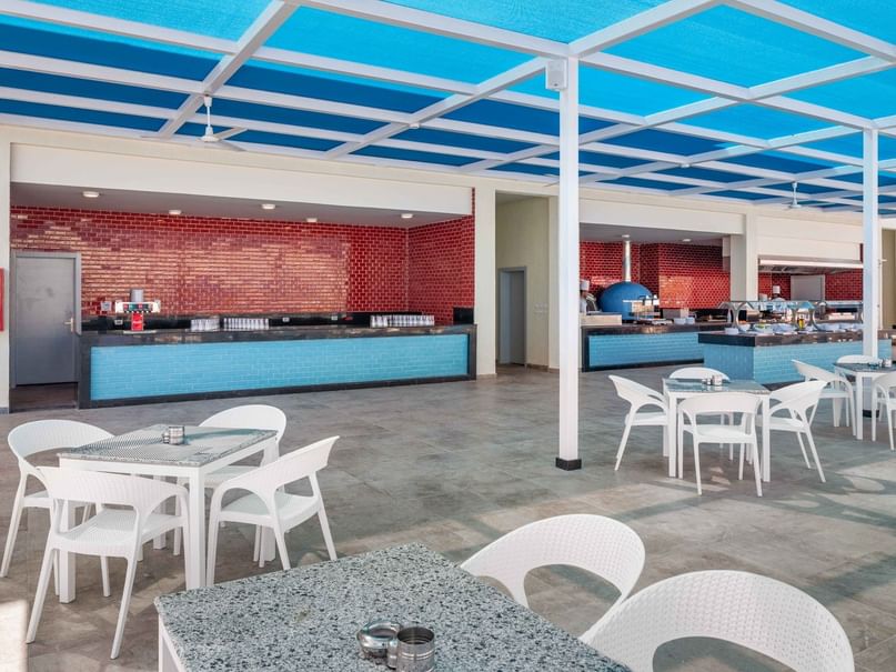 White tables and chairs under a blue canopy at Aqua Park Bar, Albatros Makadi Resort in Red Sea Governorate.