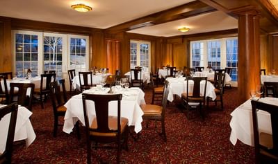 Cascades restaurant dining room with white tablecloths, wooden chairs, and large windows at The Stanley Hotel