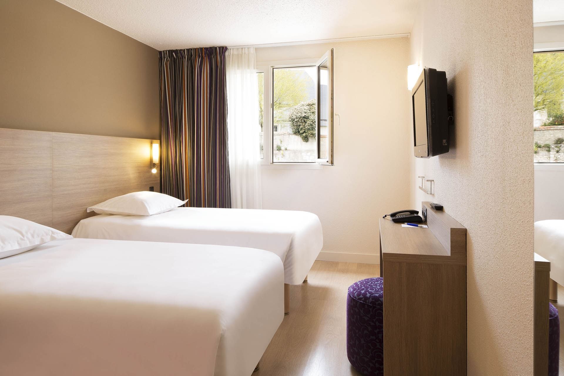 Deux lits et télévision dans une chambre à Escale Oceania Orleans