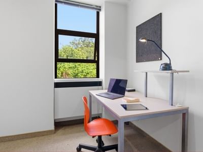 Desk with laptop, lamp, and chair in a room at UniLodge Stafford House.
