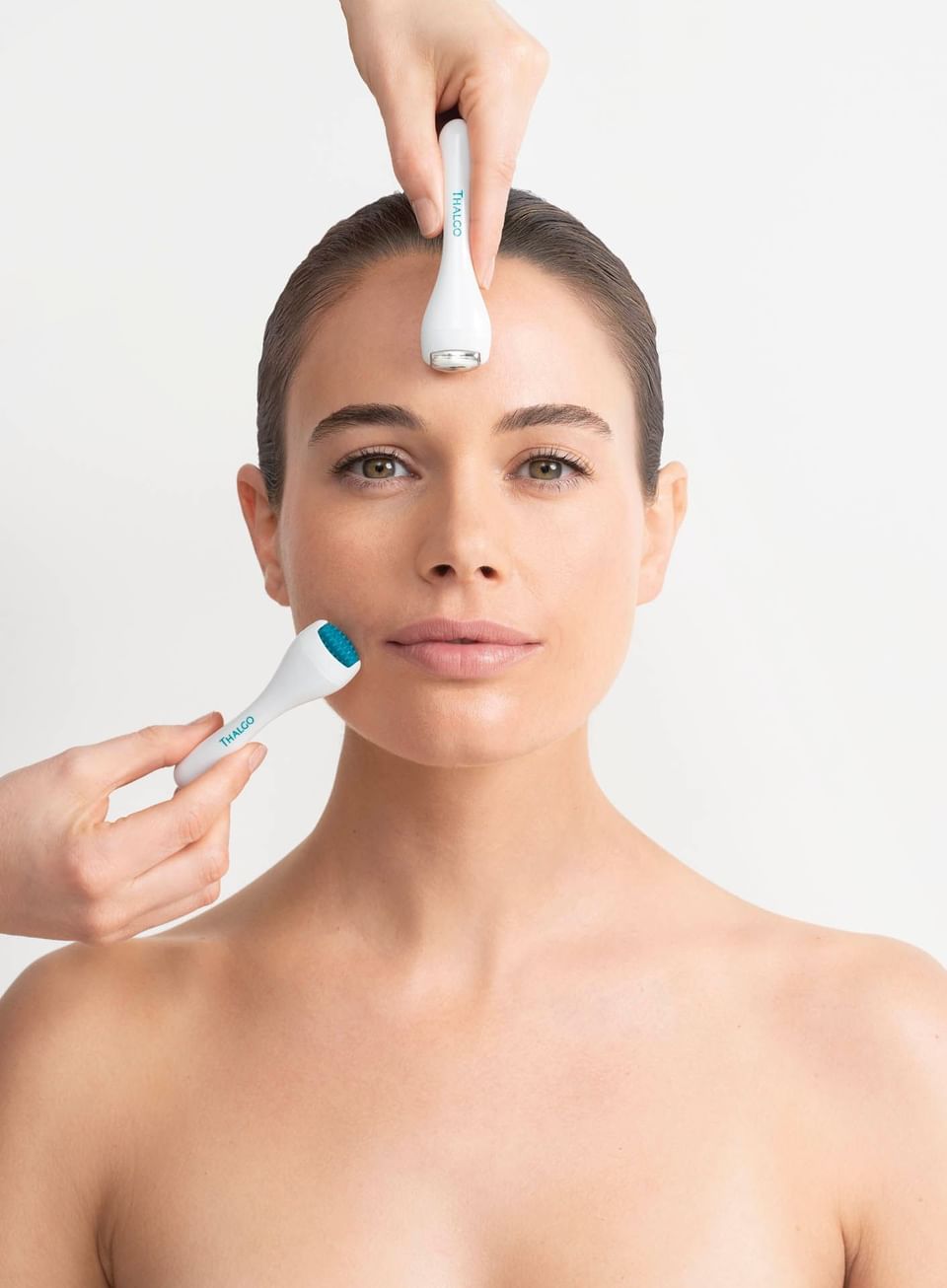 Woman receiving a facial while holding beauty devices at Thalgo Spa, The Saujana Hotel Kuala Lumpur