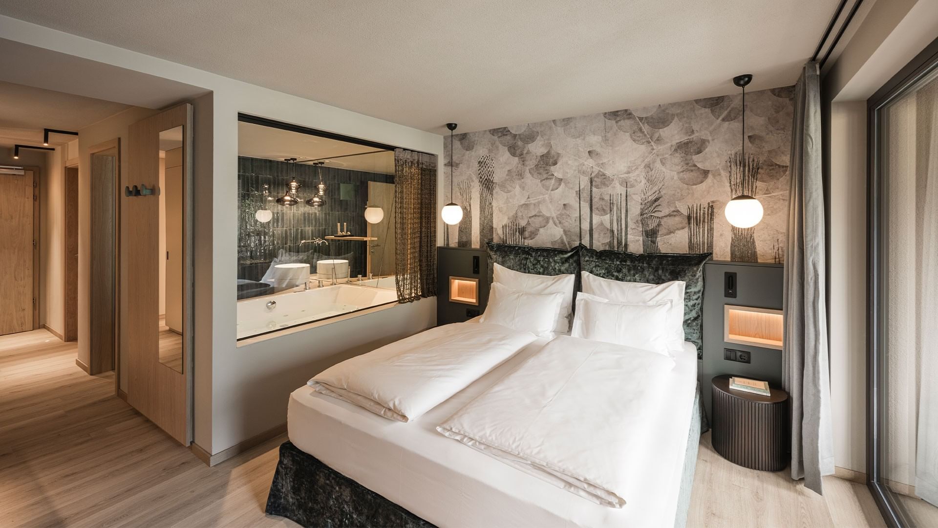 Hotelzimmer mit großem Bett, weißen Laken, Spiegel, Badewanne und moderner Einrichtung.