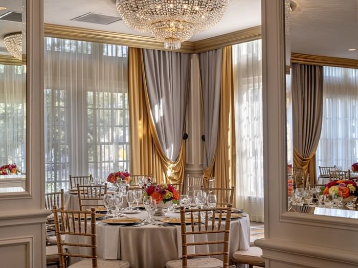 Table with flowers by gold drapes under a crystal chandelier in Crystal Ballroom at Warwick Melrose Dallas