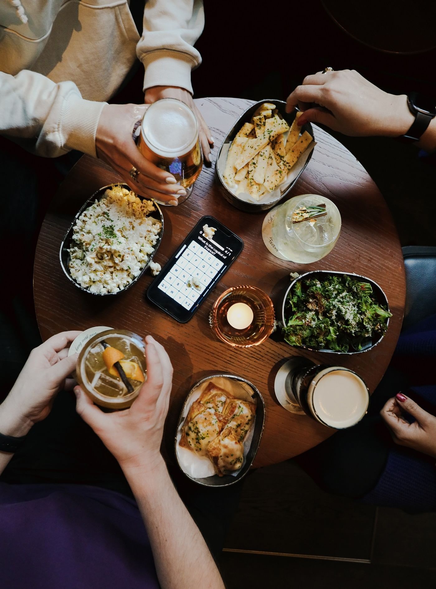 Friends enjoying drinks and salad with popcorn at Joshua's Tavern at The Londoner