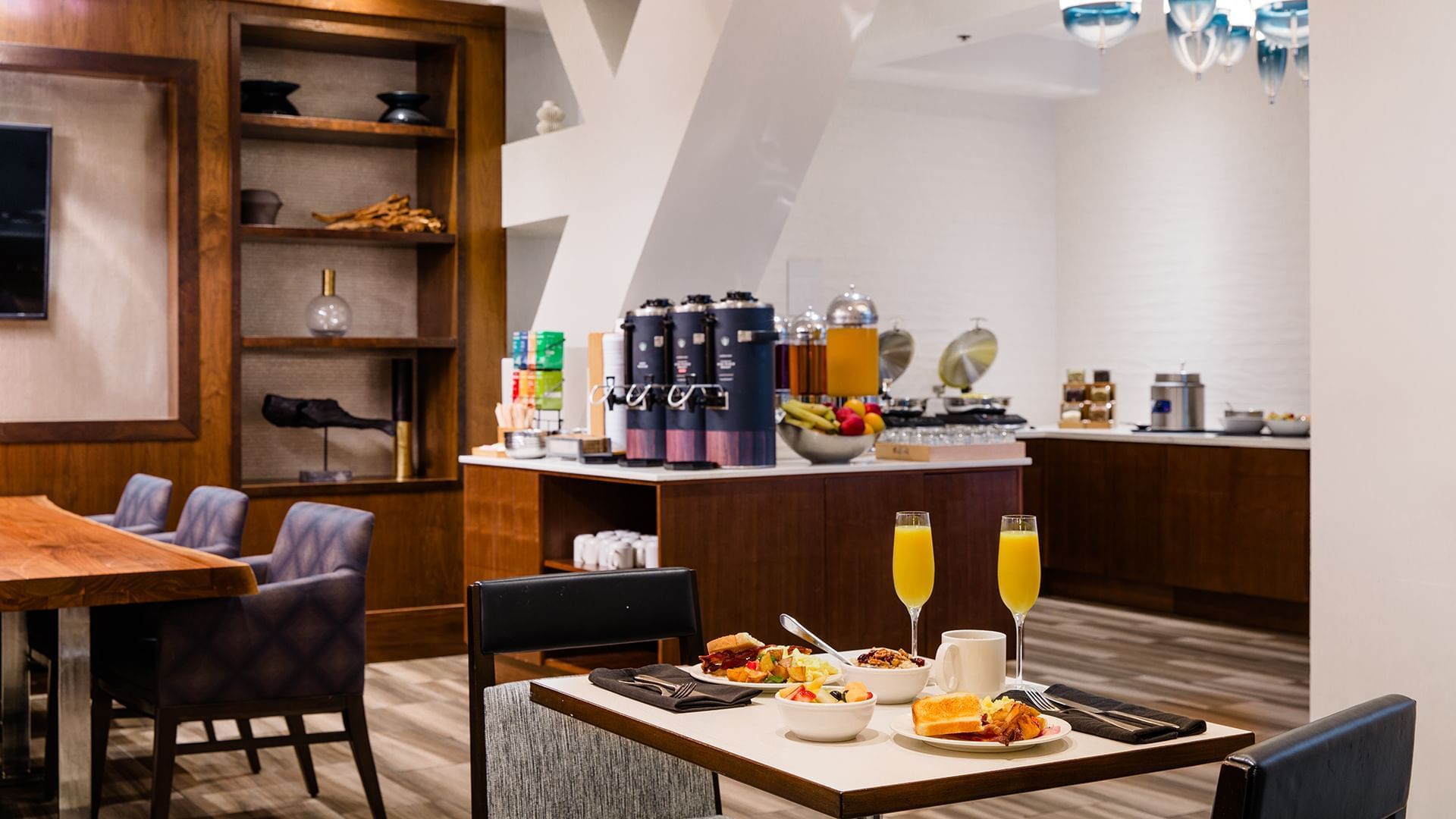 A breakfast buffet with a table set for two, featuring a variety of food and drinks.