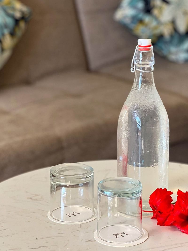 Bottle of water with two glasses and red flowers on table at The Naviti Resort in Korolevu.