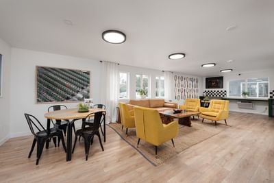 Modern living room with plush seating, a wooden dining table, and tennis racquet wall art at The Varsity North
