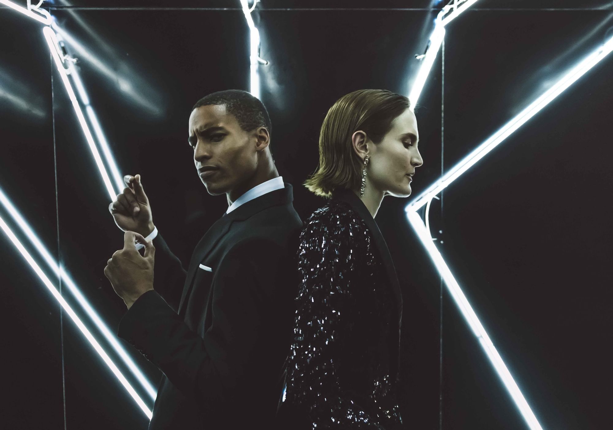 Couple in black attire standing back to back with neon lights at Sofitel Brisbane Central