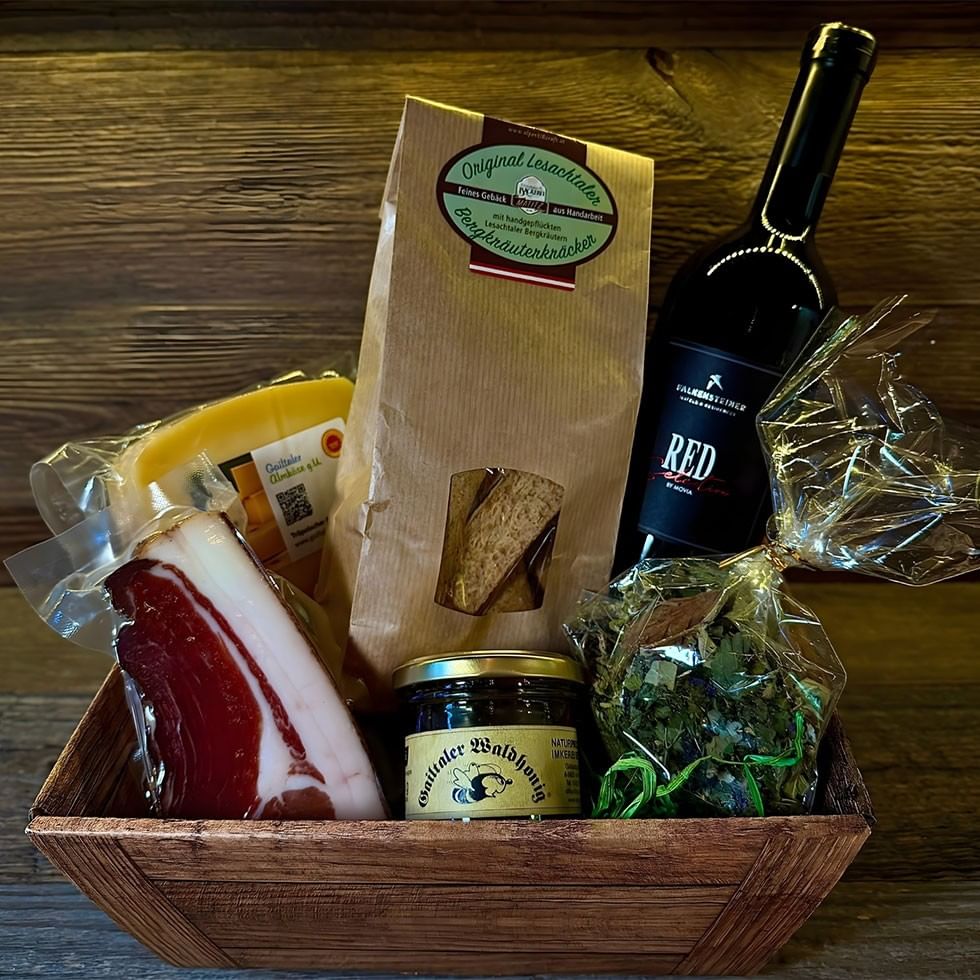 Holzkiste mit Wein, Wurst, Käse und Leckereien des Viva la Carnica Genusspakets.