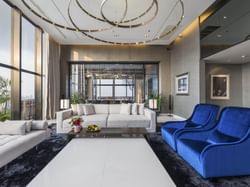 A contemporary living room featuring blue chairs and a spacious glass window discover city view.