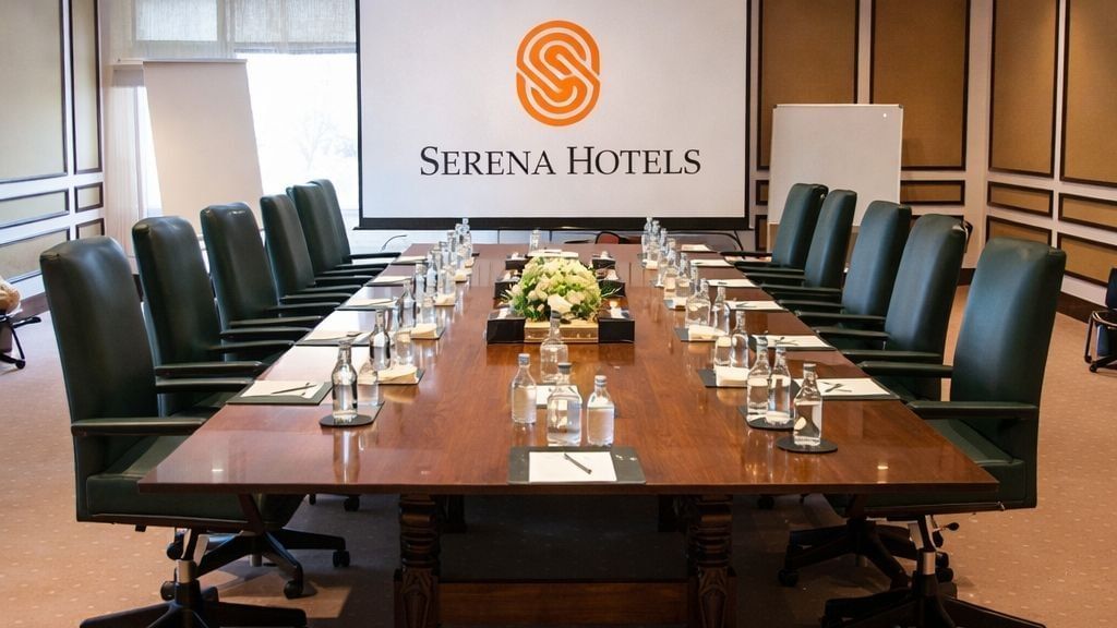 Modern conference room with plush green chairs and projection screen for unique conference venues at Serena Hotels & Resorts