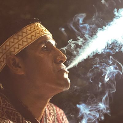 A person in a traditional outfit blowing smoke at Hotel Sumaq