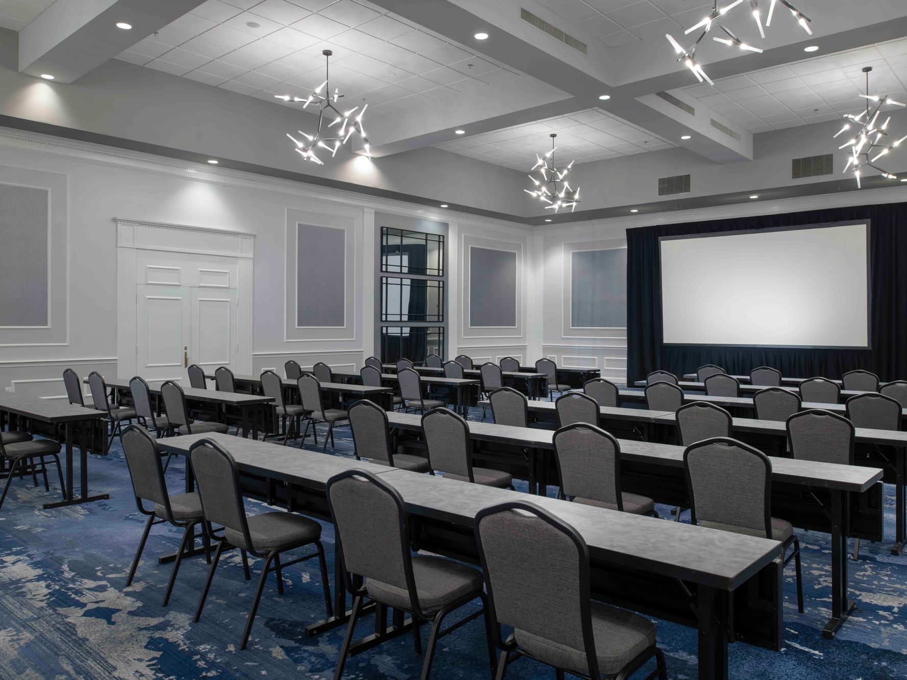 Meeting Room with Classroom Style tables and chairs facing a projector screen