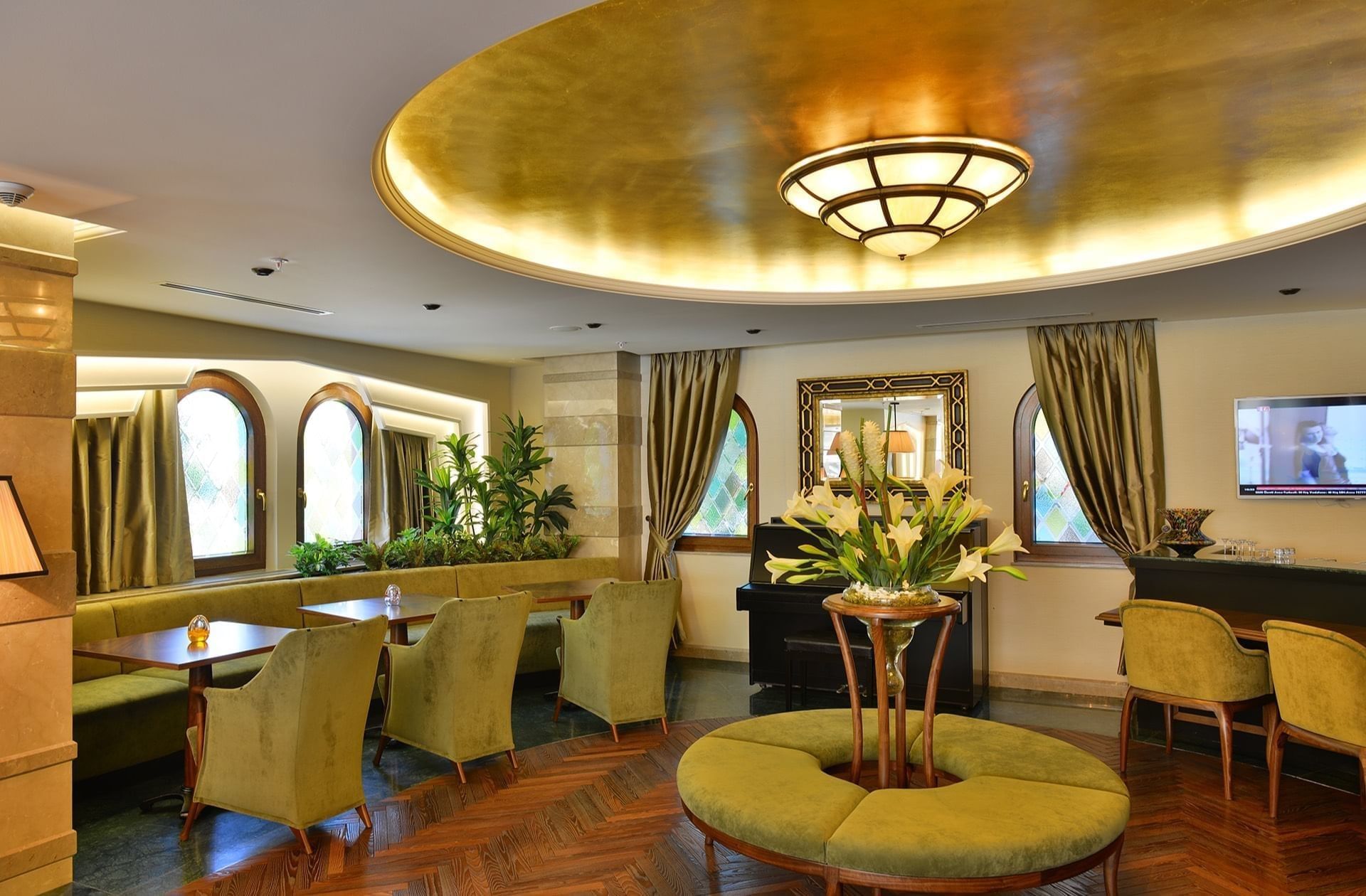 Lobby Lounge features green armchairs by an round table under a golden ceiling at Warwick Ankara
