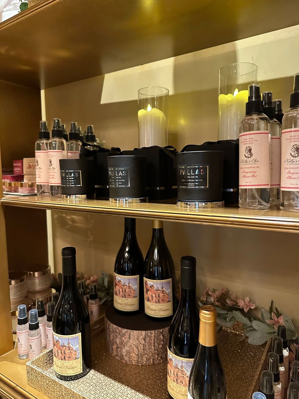 Luxury spa retail display featuring black Pallas candles, wine bottles, and scented body mists at Kelly's Spa