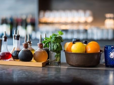 Bitters bottles by a bowl of citrus and fresh mint on a bar counter in The European at Warwick San Francisco
