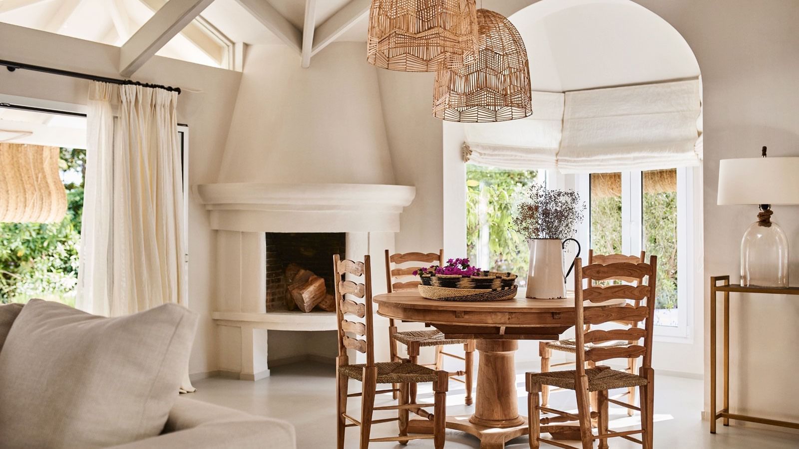 Casabel dining room with rustic wood table, straw chairs, and stucco fireplace at Marbella Club