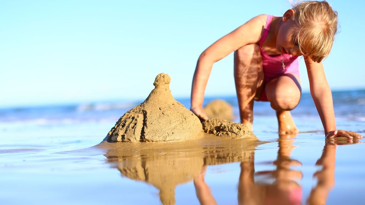 child building a sandcastle on the beach