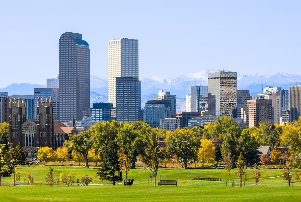 City skyscrapers by City Park denver under snow-capped mountains near Warwick Denver