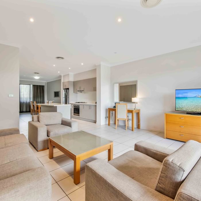 Two Bedroom Apartment living room with sofas, TV, and open kitchen area at Mercure Kooindah Waters
