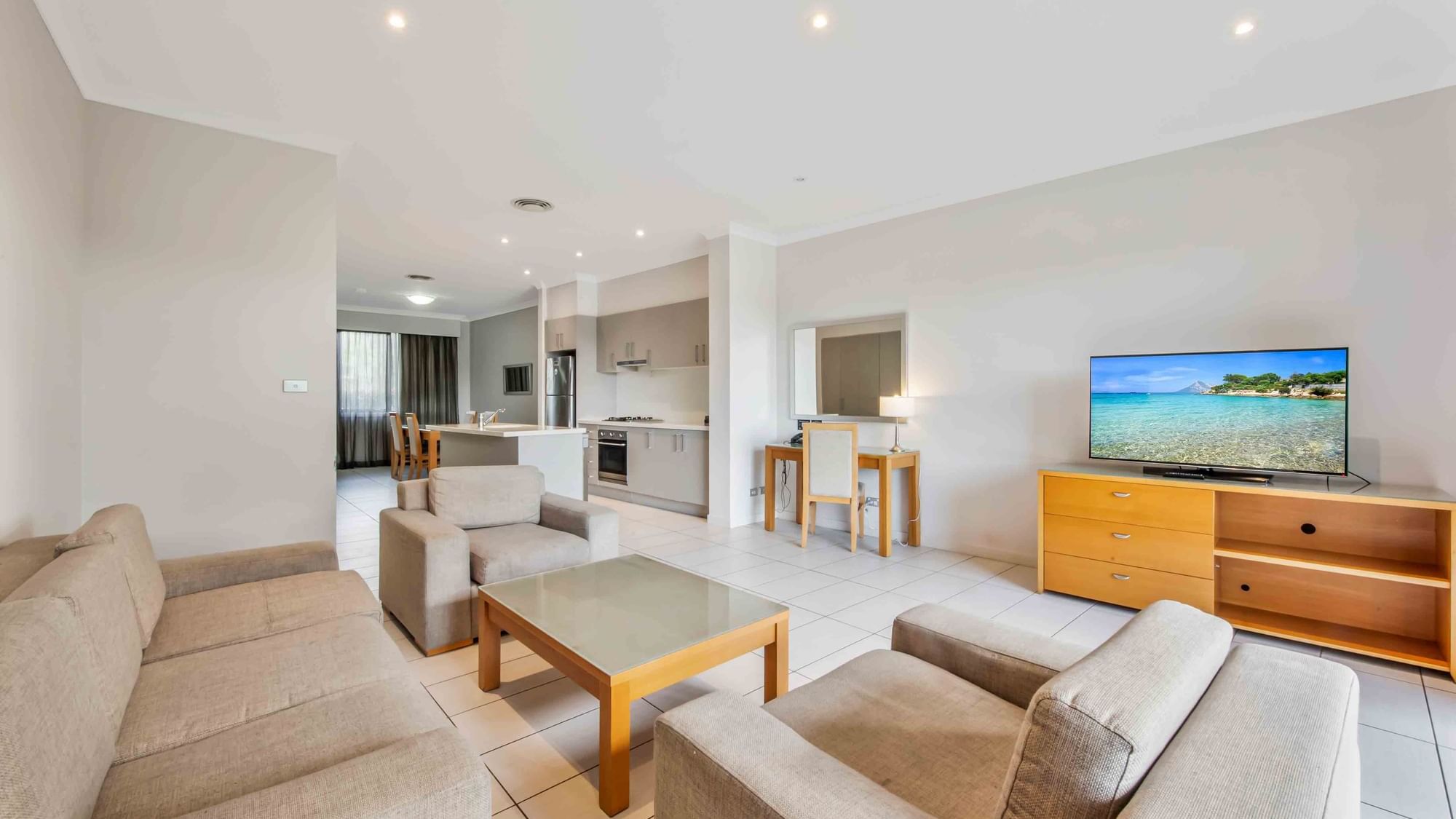 Two Bedroom Apartment living room with sofas, TV, and open kitchen area at Mercure Kooindah Waters