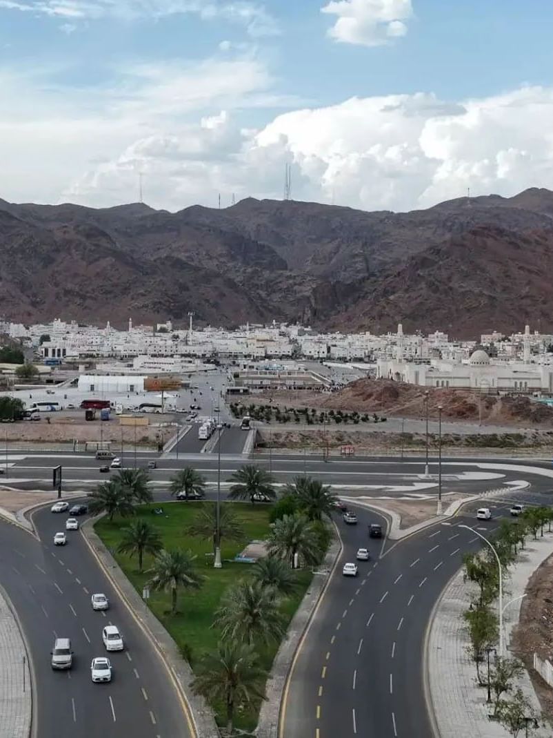 Aerial view of Mount Uhud with palm trees & mountains, and white buildings at Saja Warwick Madinah