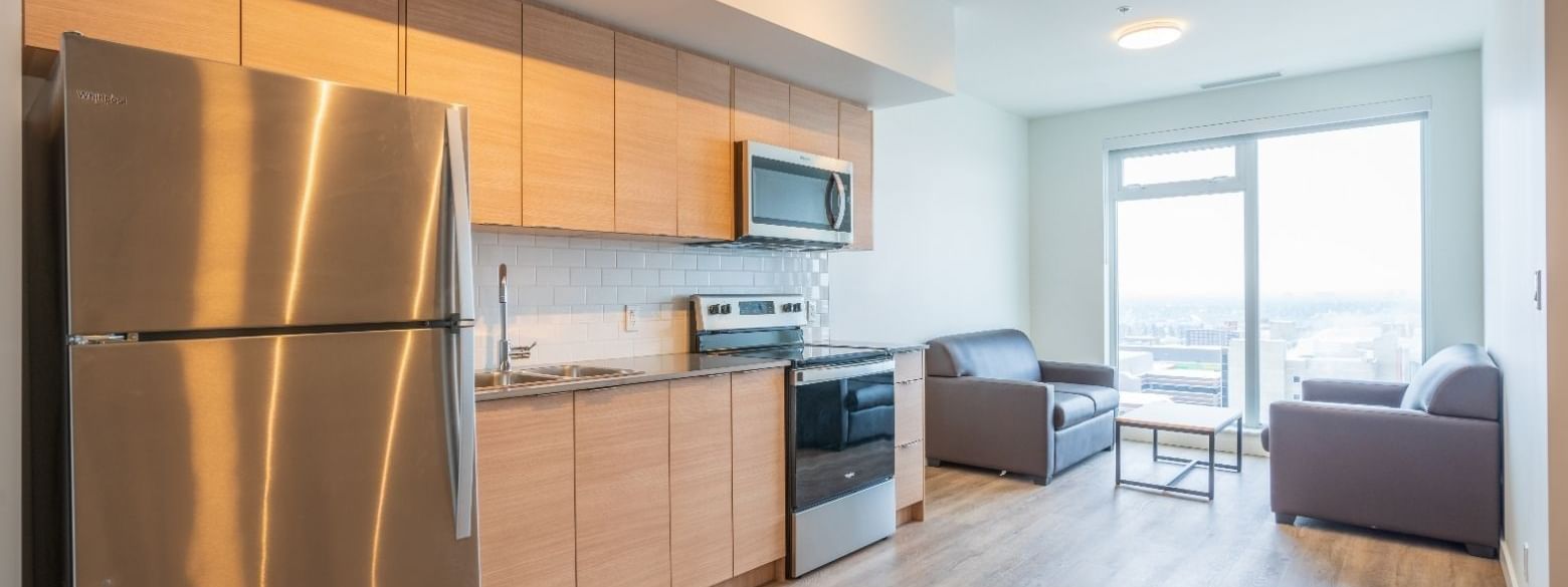 A sleek full sized kitchen and cozy sitting area with a view to a snowy cityscape.