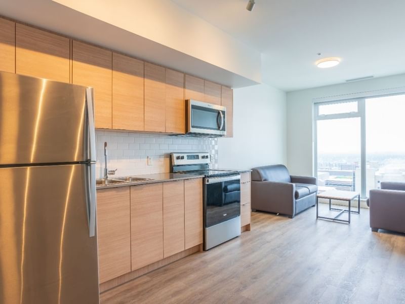 A sleek full sized kitchen and cozy sitting area with a view to a snowy cityscape.