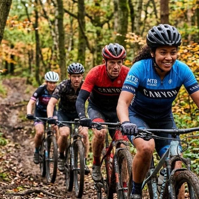 Four cyclists riding mountain bikes on a trail in a wooded area featured in our article on Cycle September Bracknell..