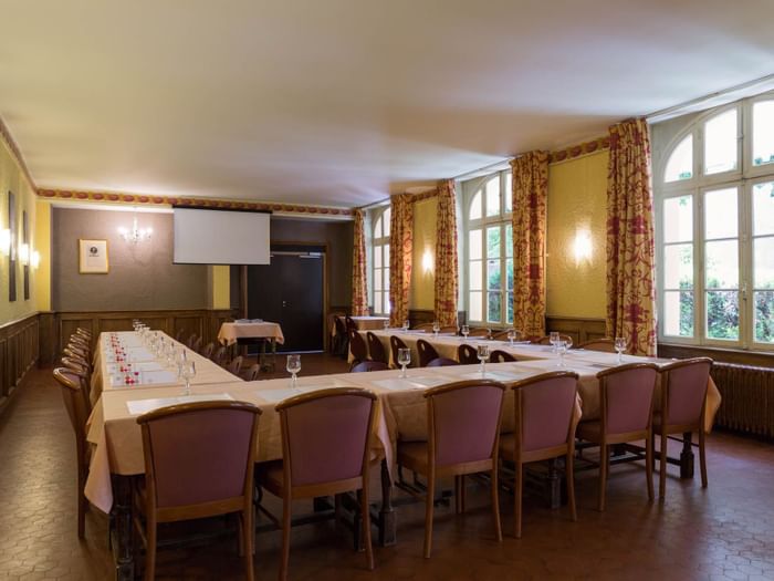 A hall perpared for a meeting with a set table and purple chairs