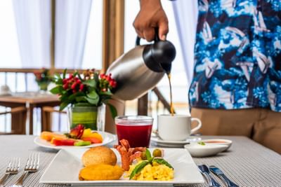 A waiter pouring coffee into a cup at Hotel Isla Del Encanto