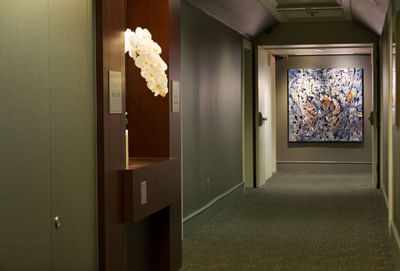 Hallway at The St. Regis Hotel Vancouver with orchids, room numbers, and an abstract painting on the walls