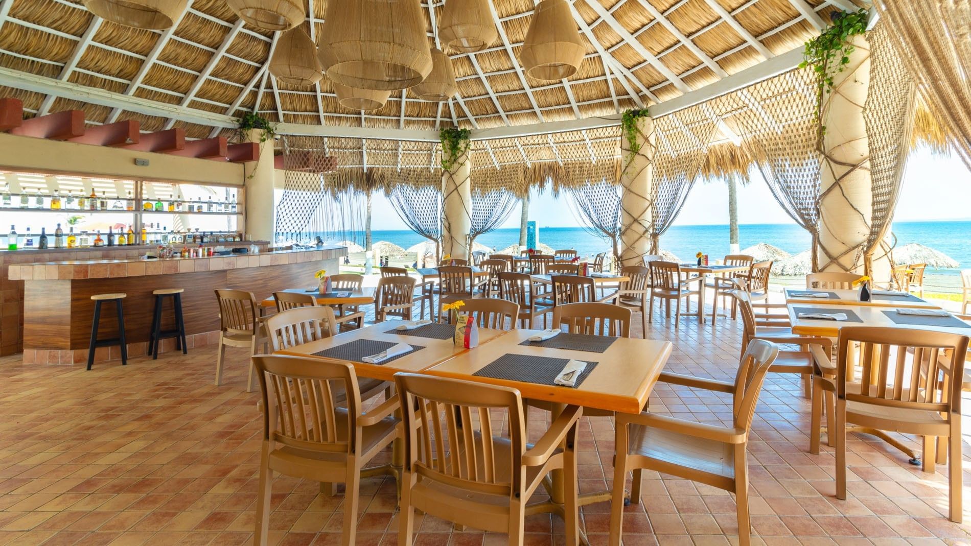 Beachfront La Vela restaurant with a thatched roof, wooden tables, and vast ocean scenery at Camino Real Veracruz