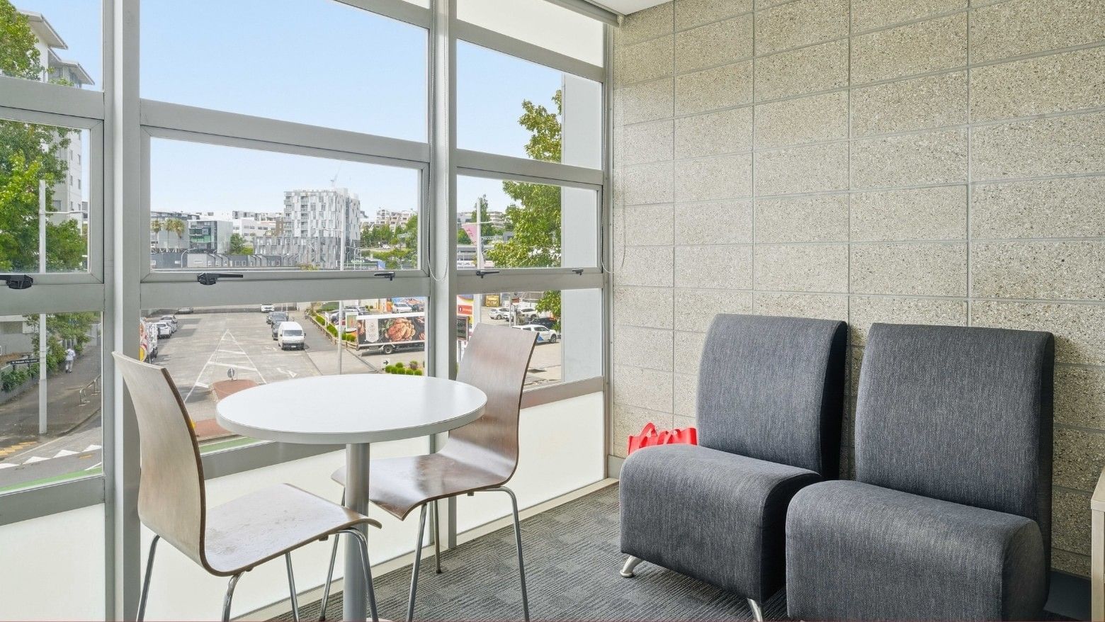 Lounge with two chairs and a table in front of a large window at Student Living Auckland - Beach.