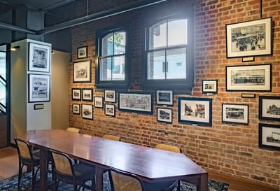 Cozy room with a long wooden table, wicker chairs, and brick walls adorned with vintage photos at Amora Herencia Riverwalk