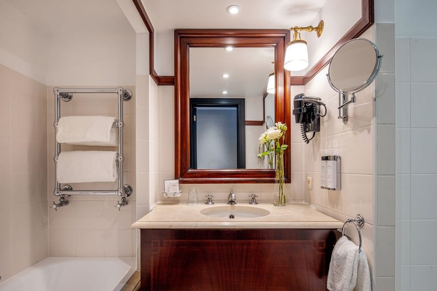 Wood vanity with marble sink and large mirror in Superior bathroom at Hotel Barsey by Warwick