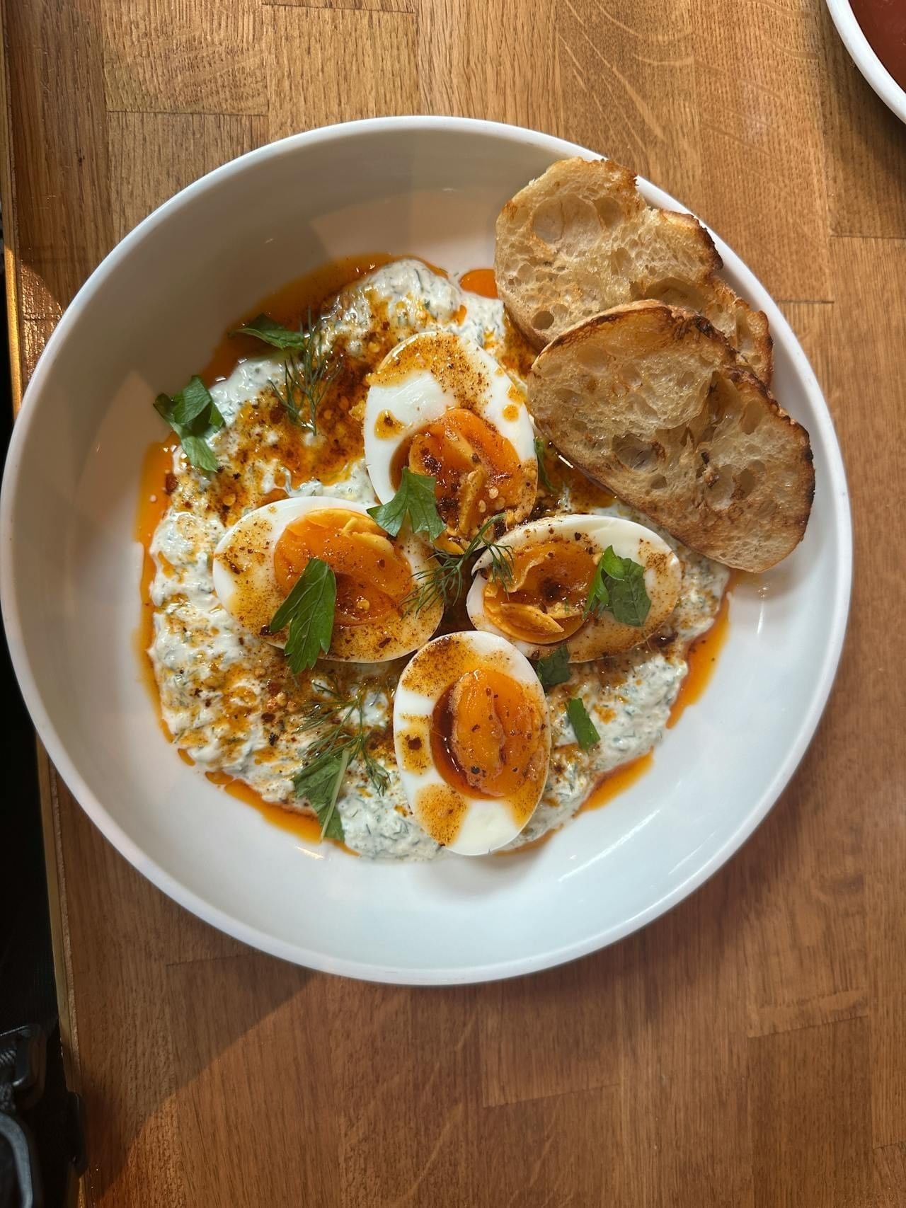 White bowl of eggs and garnish on a wooden table at Paradox Hotels and Resorts Portal