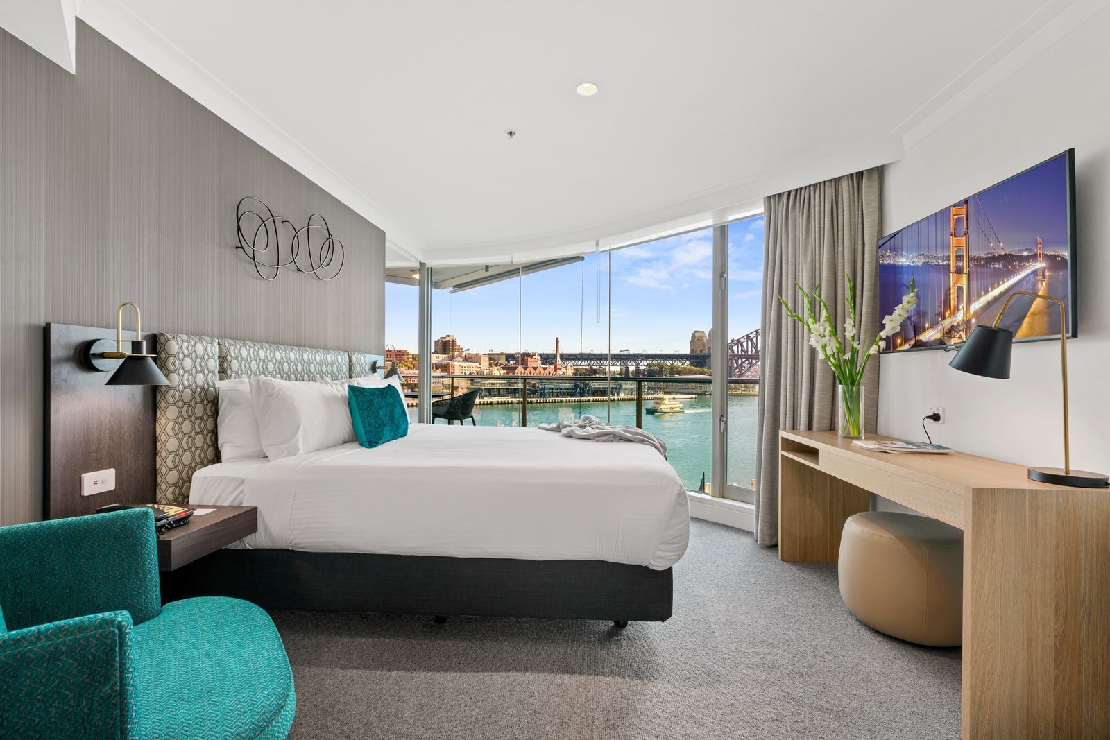 Comfy king bed with plush pillows overlooking the Sydney Harbour Bridge from a tall window at Pullman Quay Grand Sydney