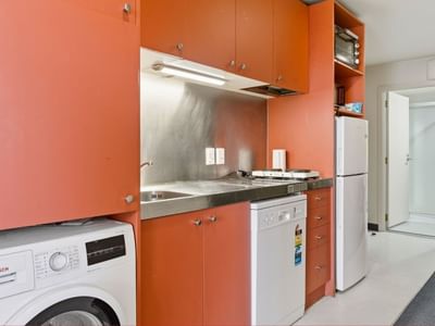 Orange kitchen with appliances and cabinets at UniLodge Stafford House.