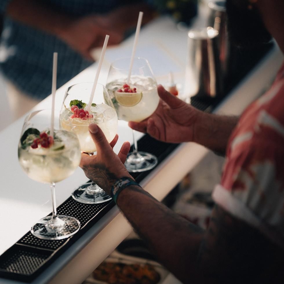 Hands toasting with gin cocktails garnished with berries and mint at Dolce Vita Afterwork event