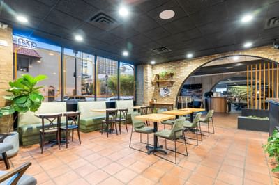 Modern Coffee Bar at The Riverwalk Plaza Hotel with green booths, wooden tables, and large windows offering a city view