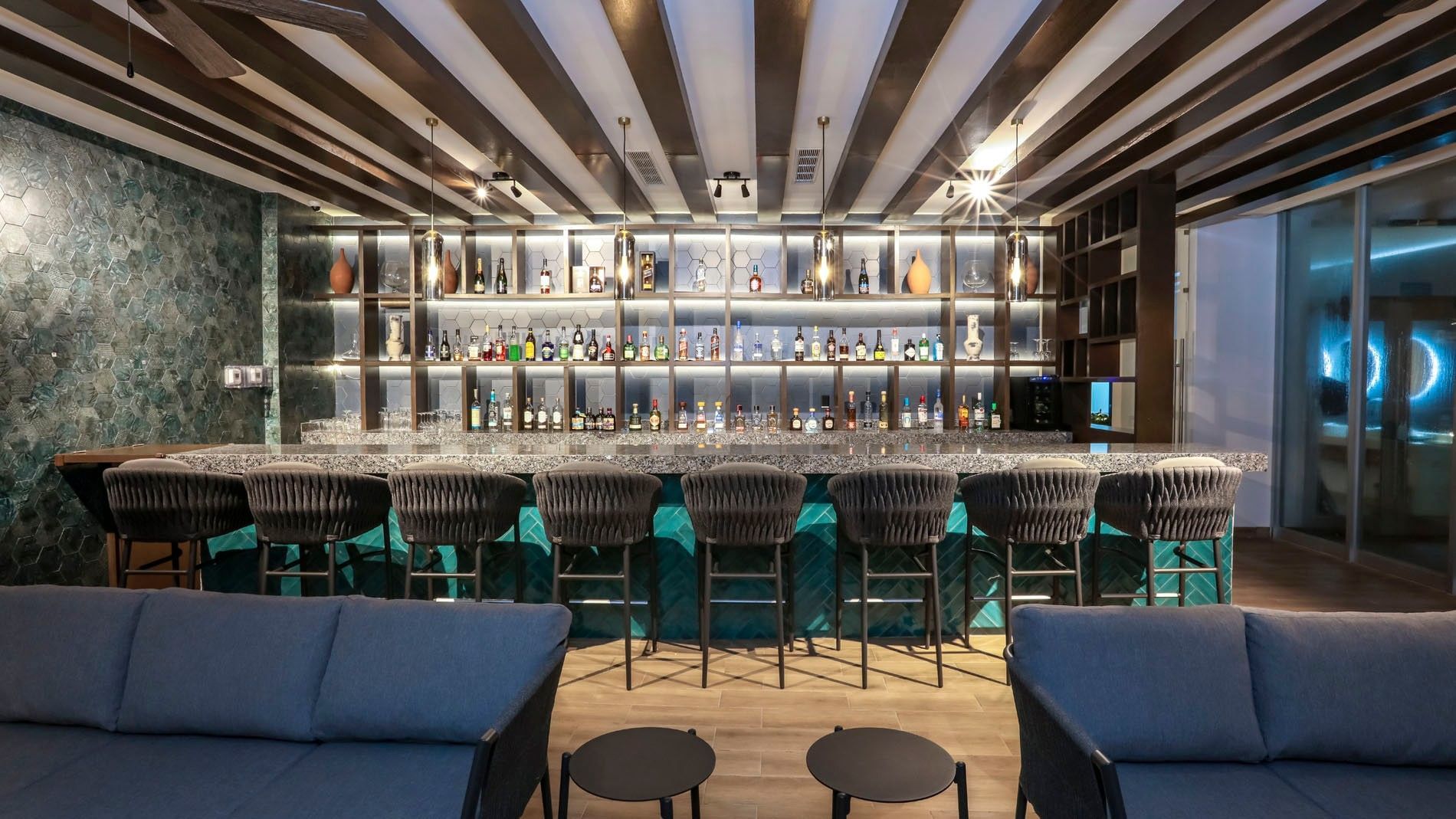 Sophisticated Blue Bar featuring teal tiles, velvet seating, and a glowing shelf at Camino Real Veracruz