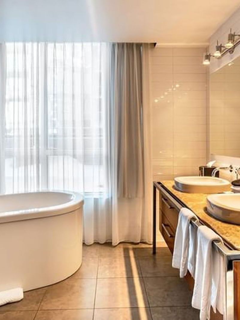 Luxurious bathroom with bathtub and double sink at Warwick Le Crystal – Montreal.