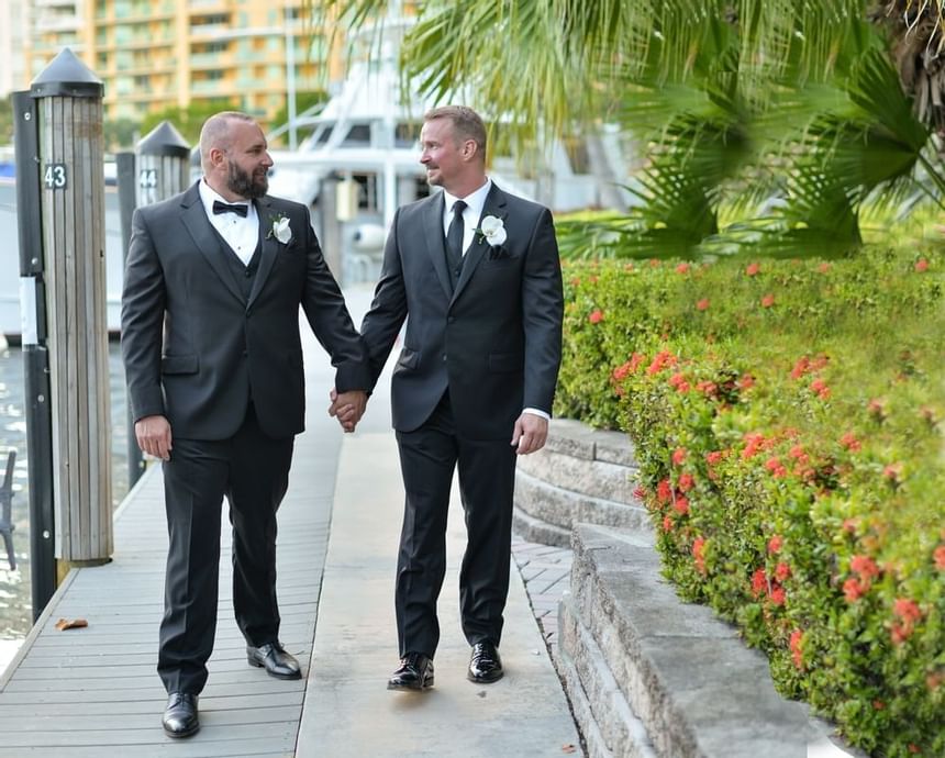 two bed in tuxedos holding hands