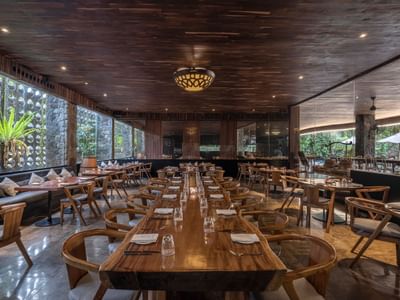 Long dining tables with chairs and decorative elements in a spacious restaurant at Peppers Seminyak