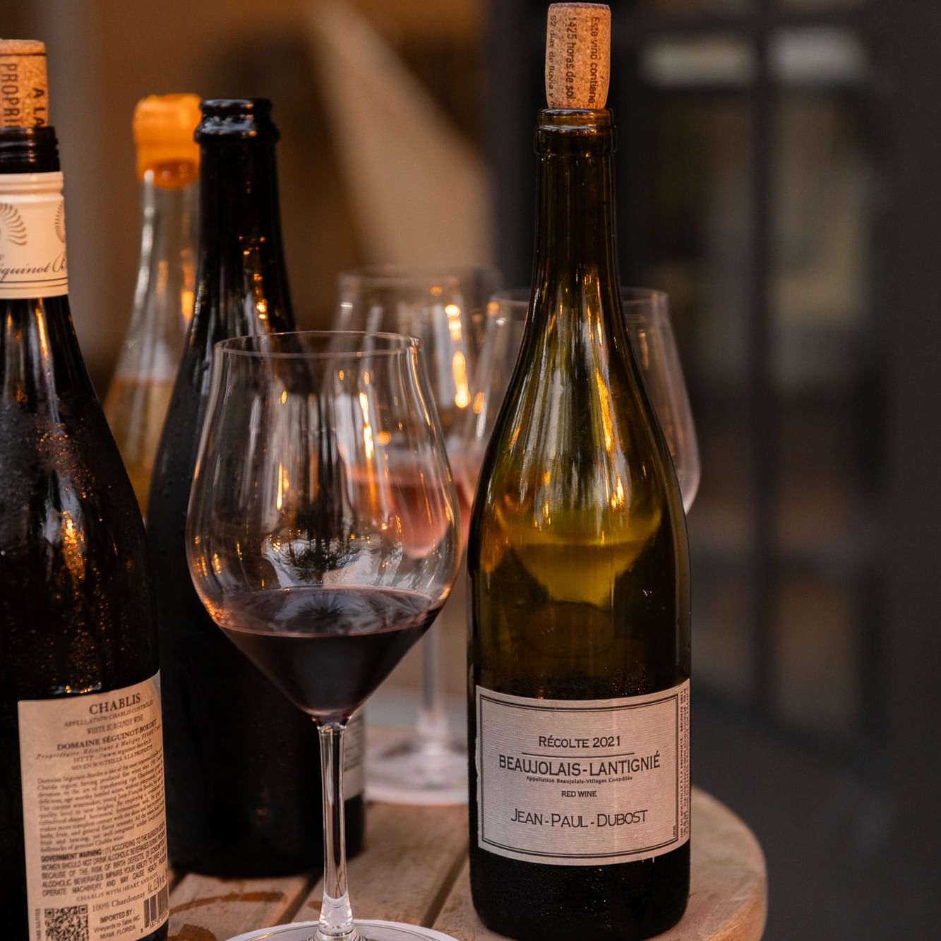 Wine bottles and filled glasses displayed on a wooden barrel for Thursday Wine Nights at Drexel.