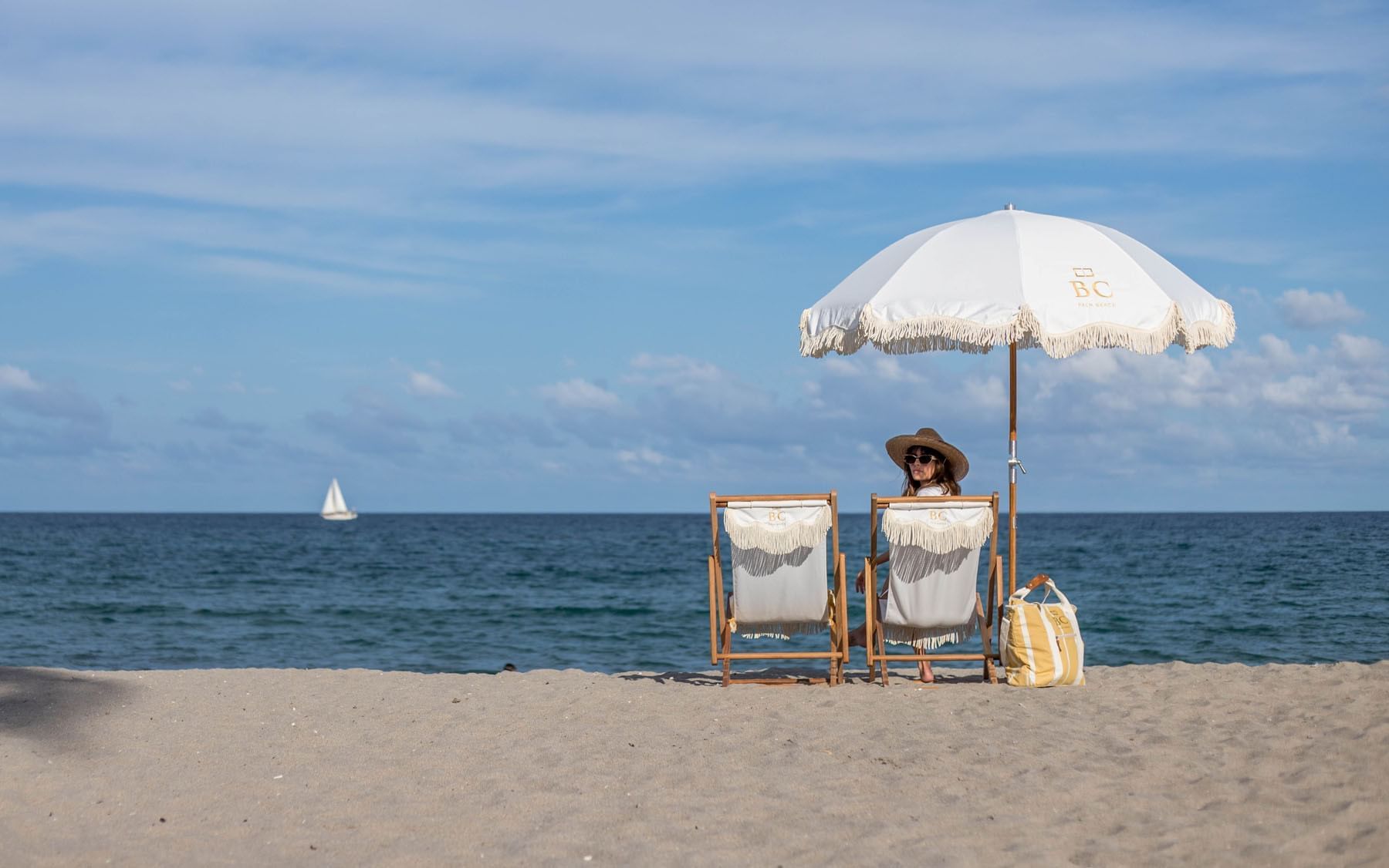 Women sit in a lounge on the private beach at Brazilian Court